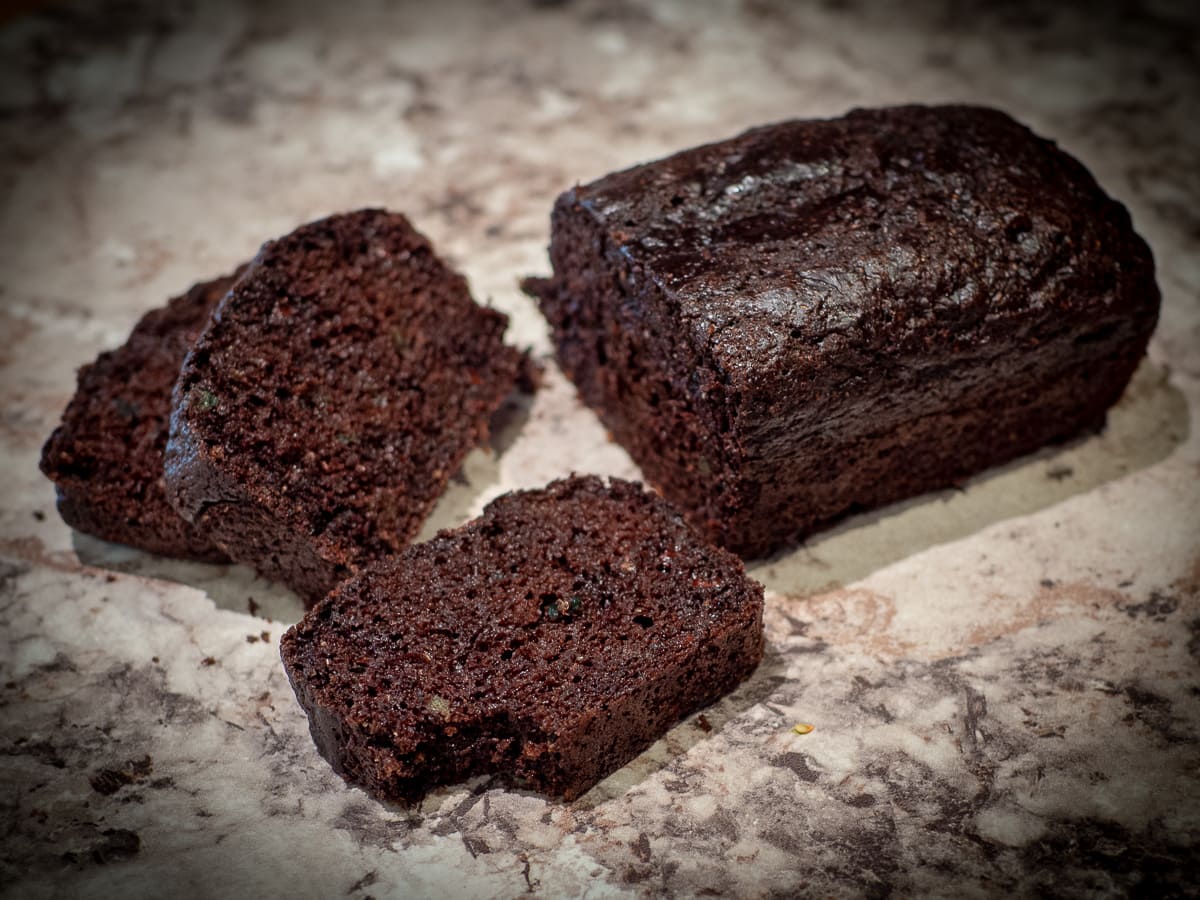 Mini chocolate zucchini loaf on a counter with a bite taken out of a slice.