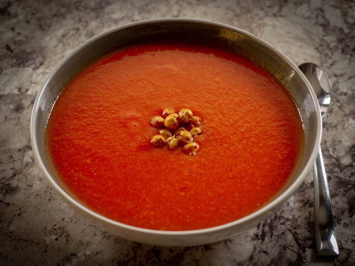 Bowl of tomato soup topped with roasted chickpeas.