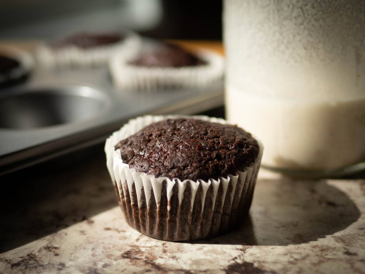 Chocolate muffin next to a glass of milk.