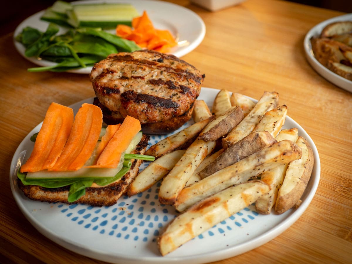 Pork banh mi burger on a plate with fries.