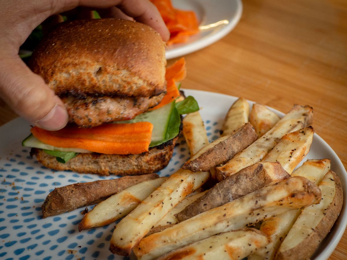 Hand assembling a pork burger.