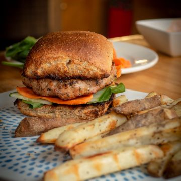 Pork burger on a plate with fries.