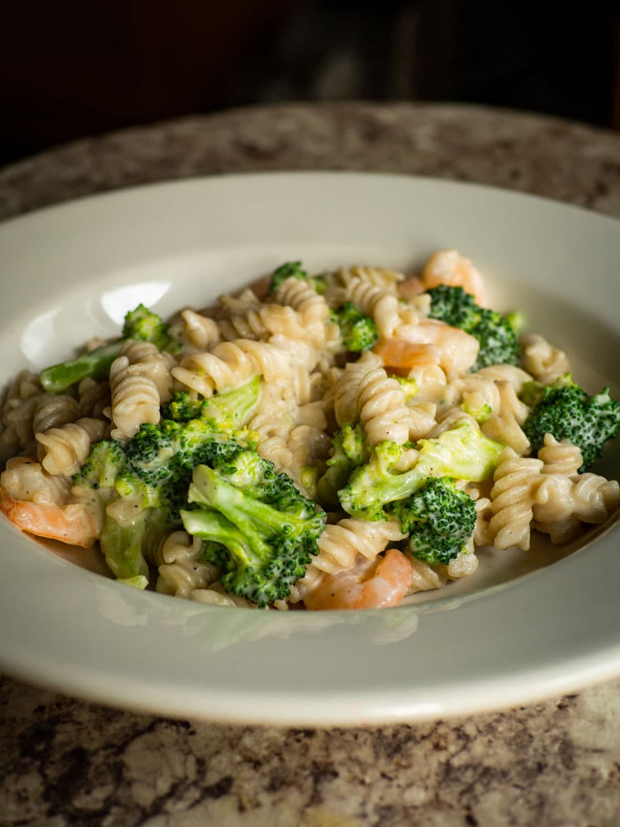 Bowl of one pot pasta with broccoli, shrimp and creamy cashew sauce.