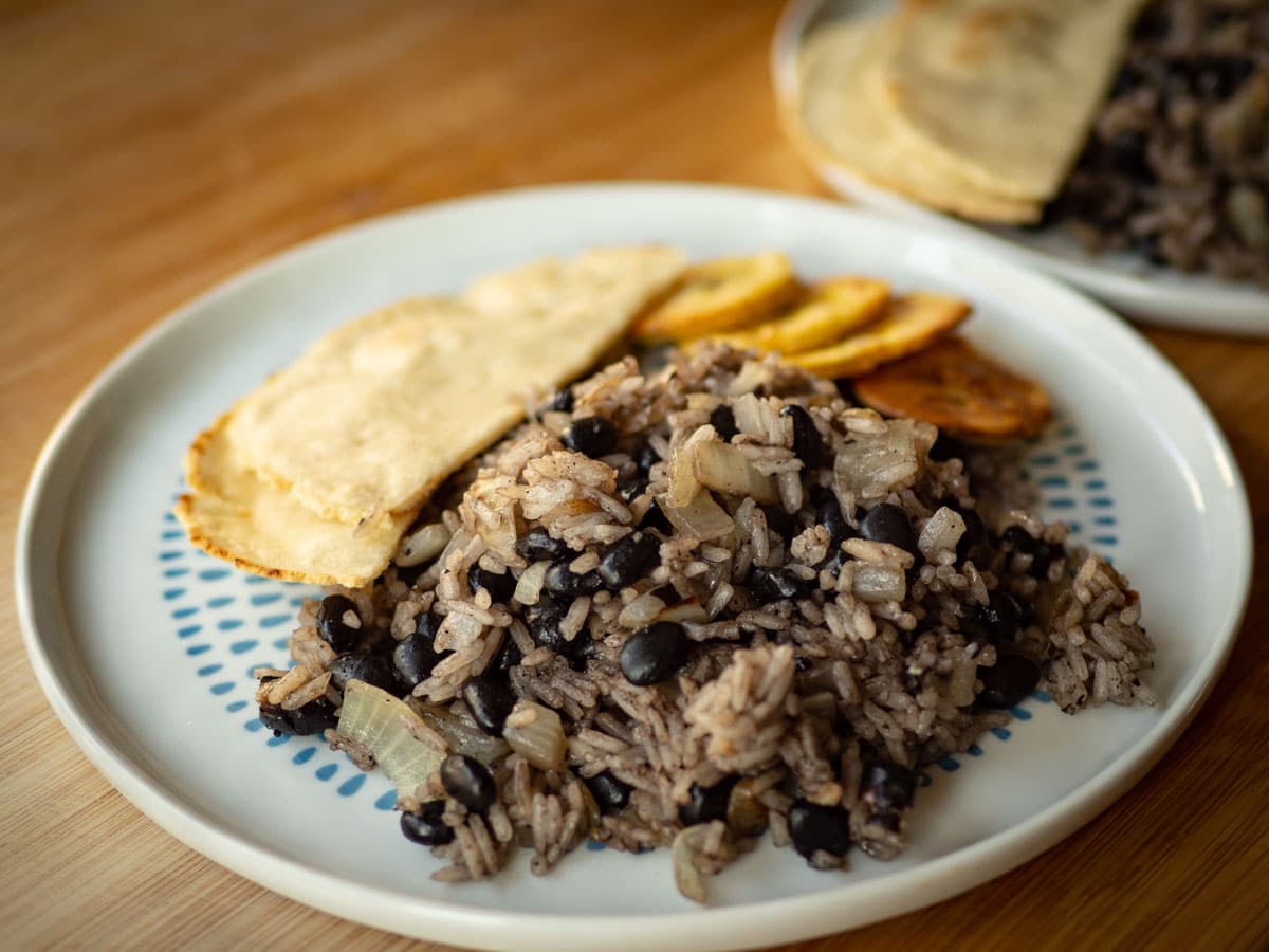 Gallo pinto on a plate with tortillas and plantains.