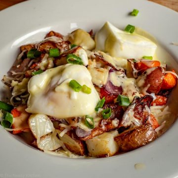 Breakfast potatoes topped with cheese, poached eggs and Hollandaise sauce.
