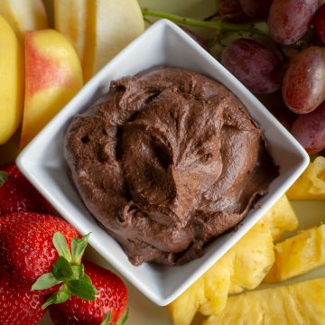 Bowl of chocolate hummus surrounded by fruit.