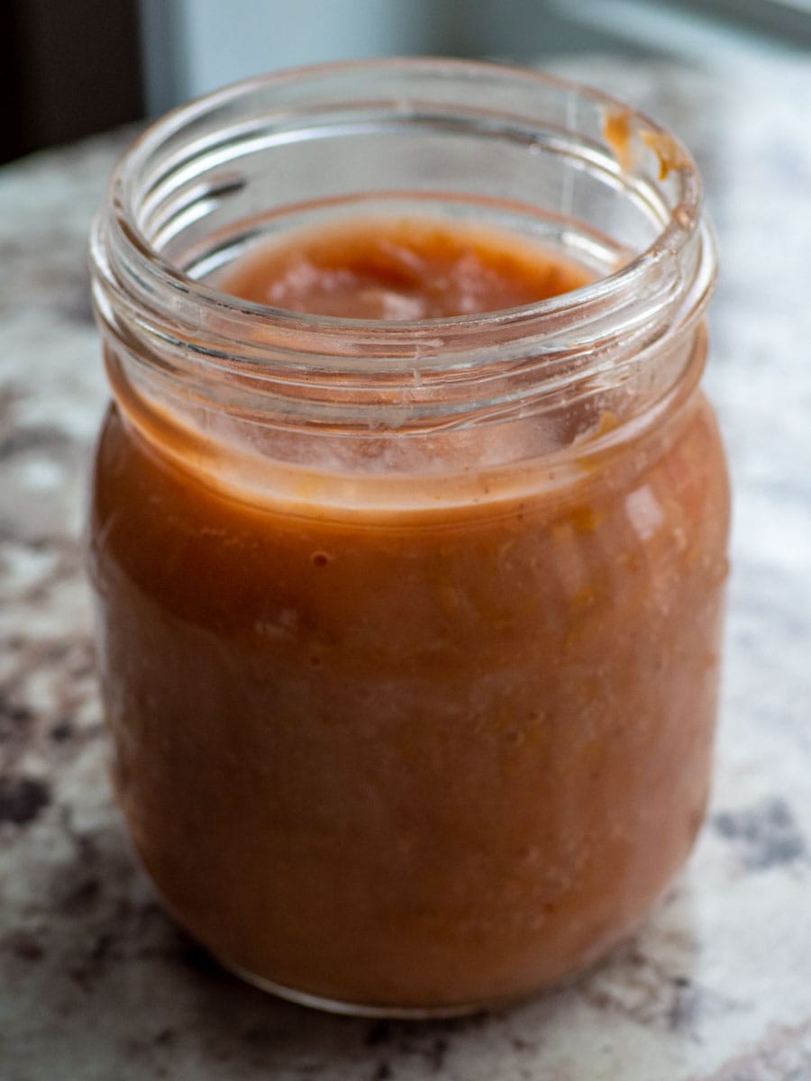 Smooth applesauce in a mason jar. The applesauce has a deep red colour since it was made without peeling.