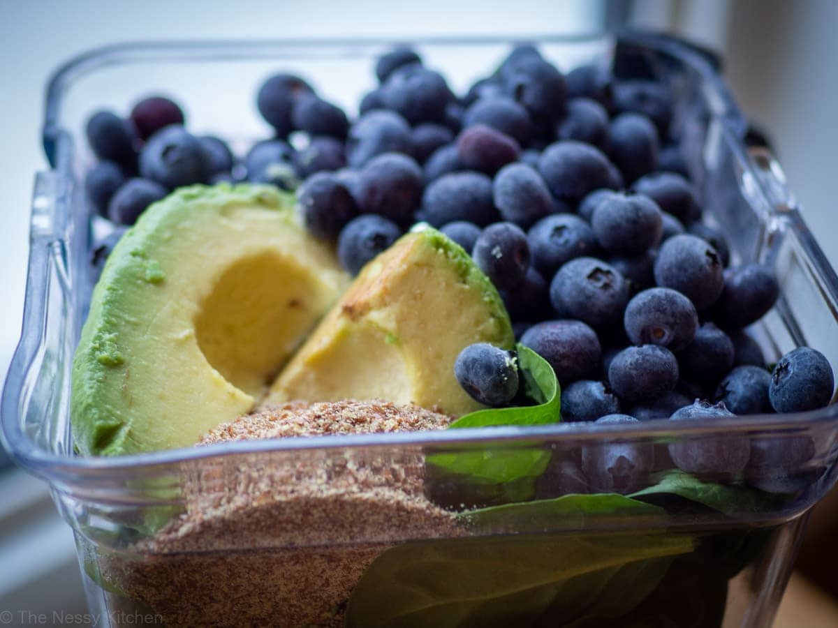 Ingredients for a blueberry avocado and spinach smoothie in a blender.