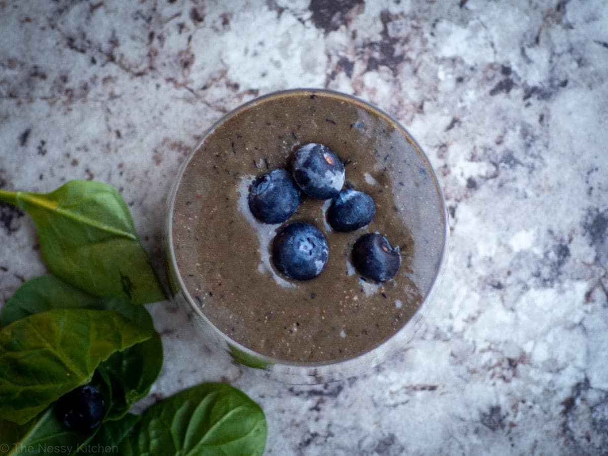 Smoothie in a glass topped with blueberries.