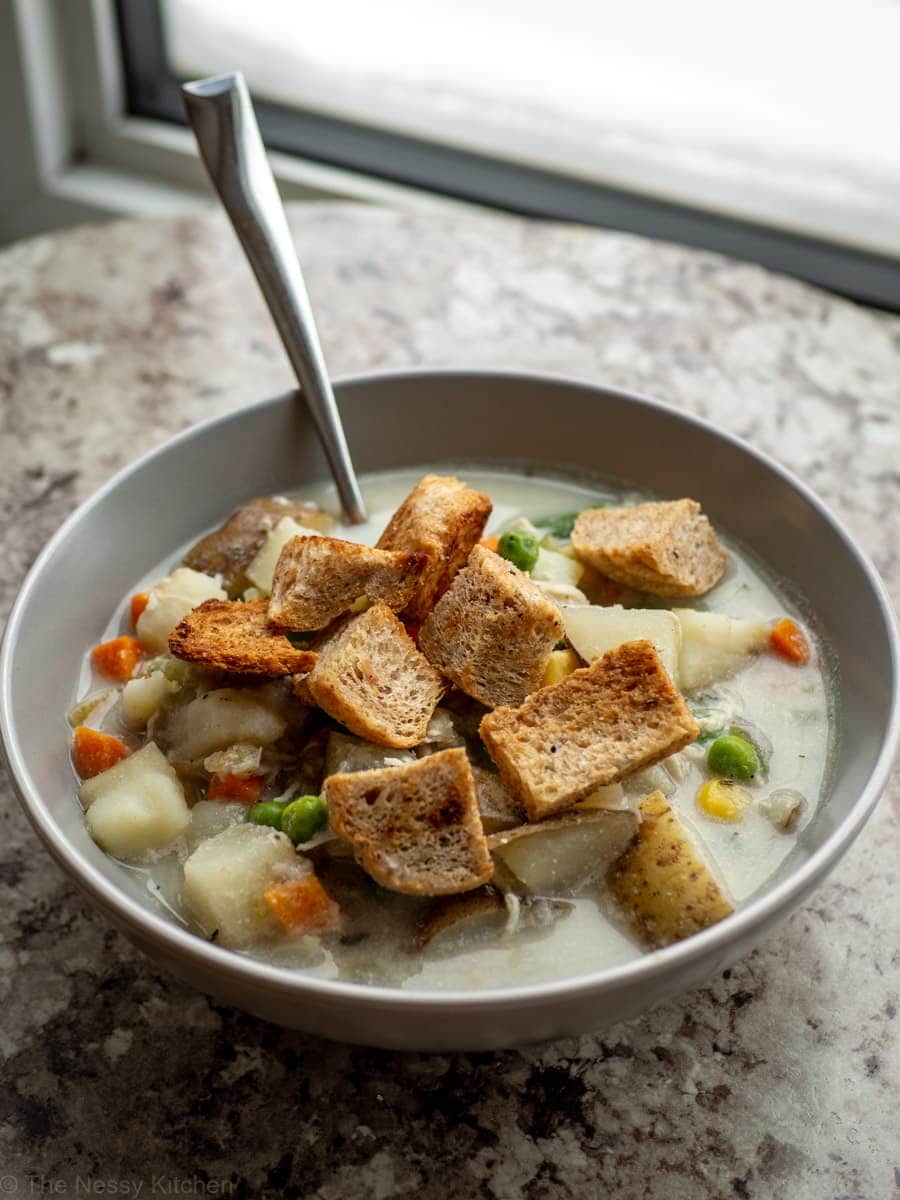 Bowl of pot pie soup topped with croutons.