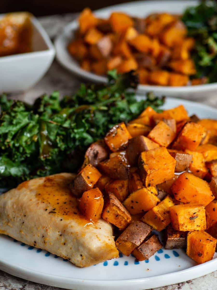 Sweet potatoes, chicken and kale on a plate with sauce.
