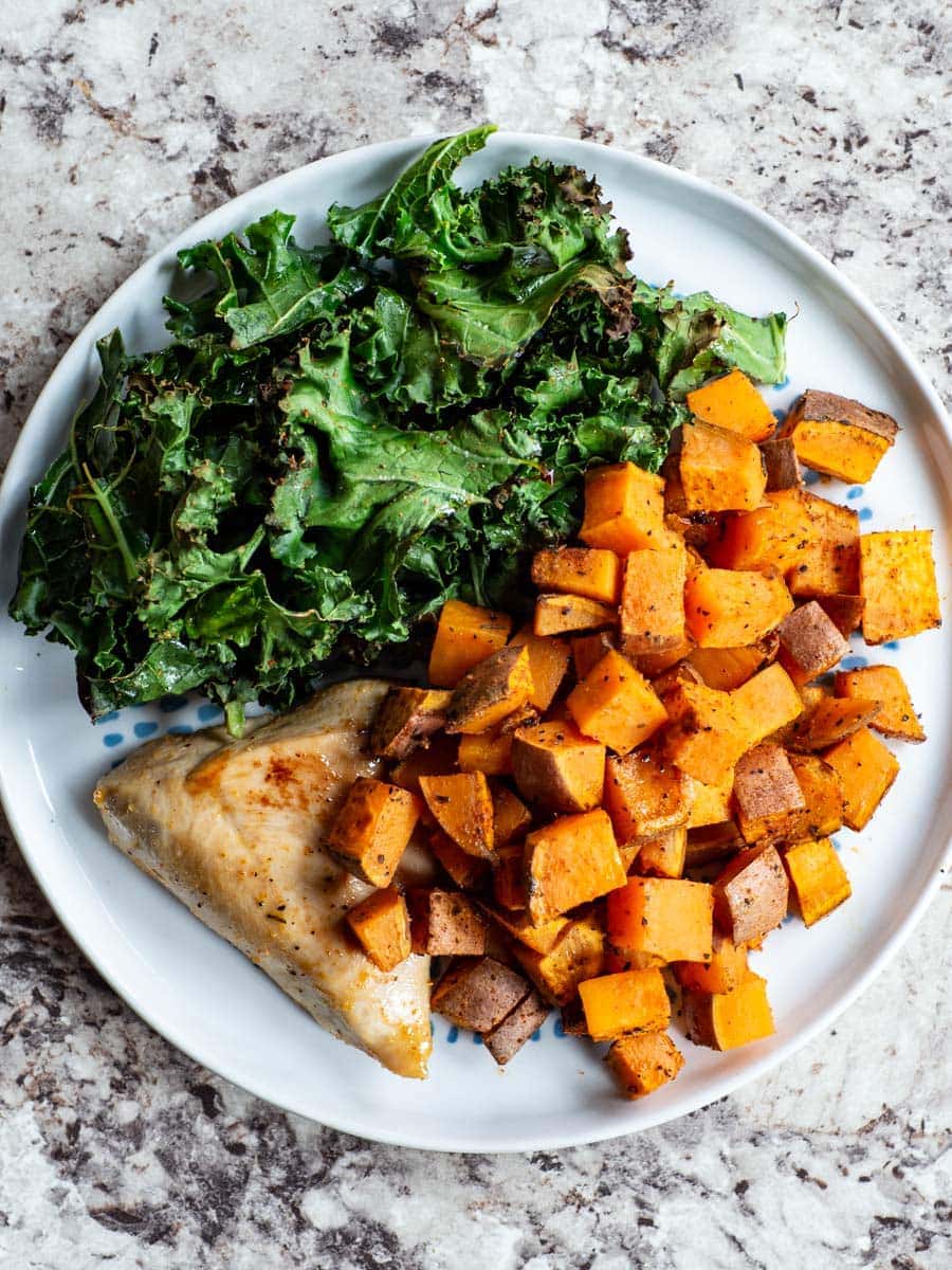 Top view of a plate with kale, sweet potatoes and a chicken breast.