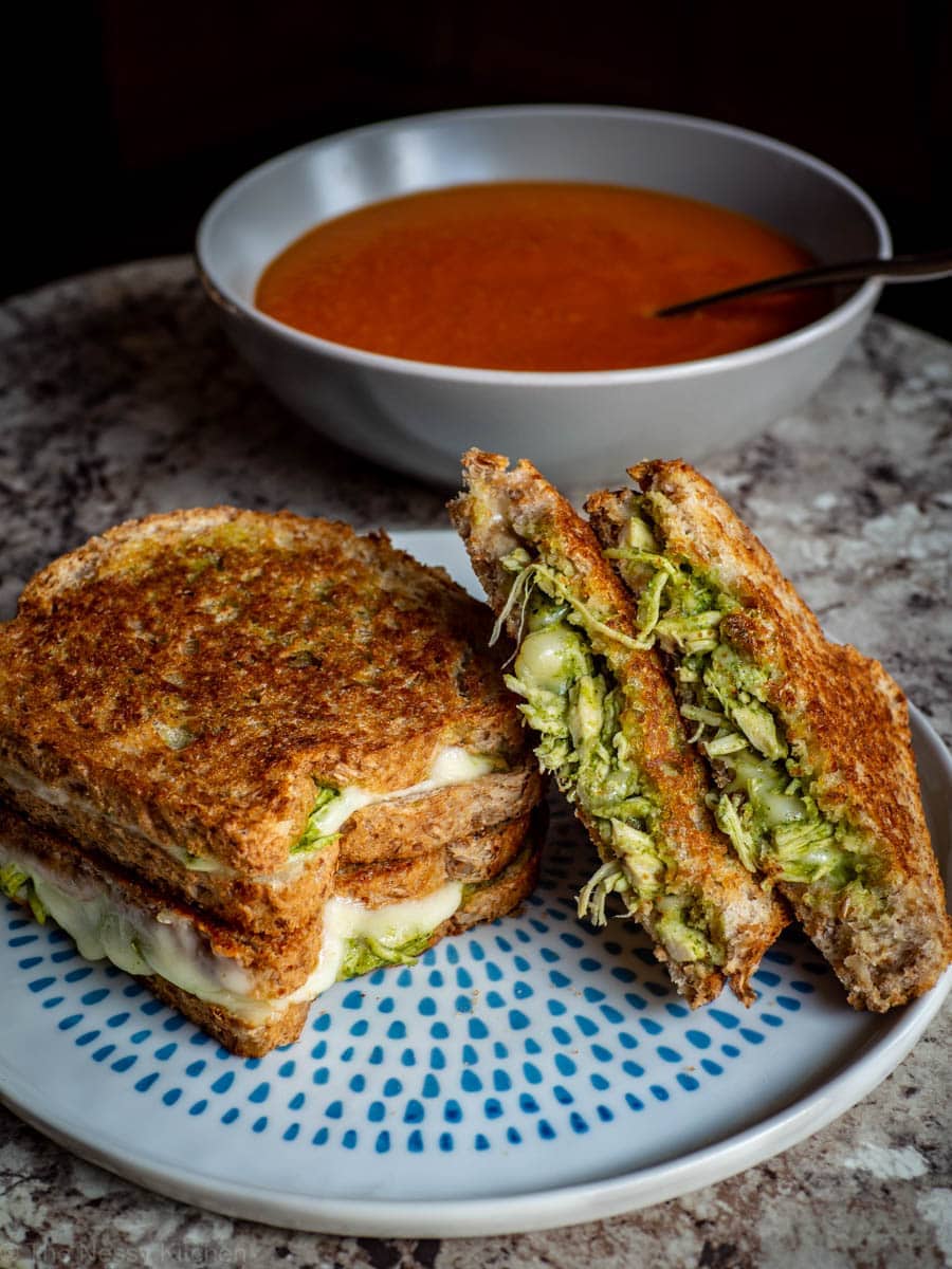 Stack of Chimichurri chicken sandwiches with a bowl of soup in the background.