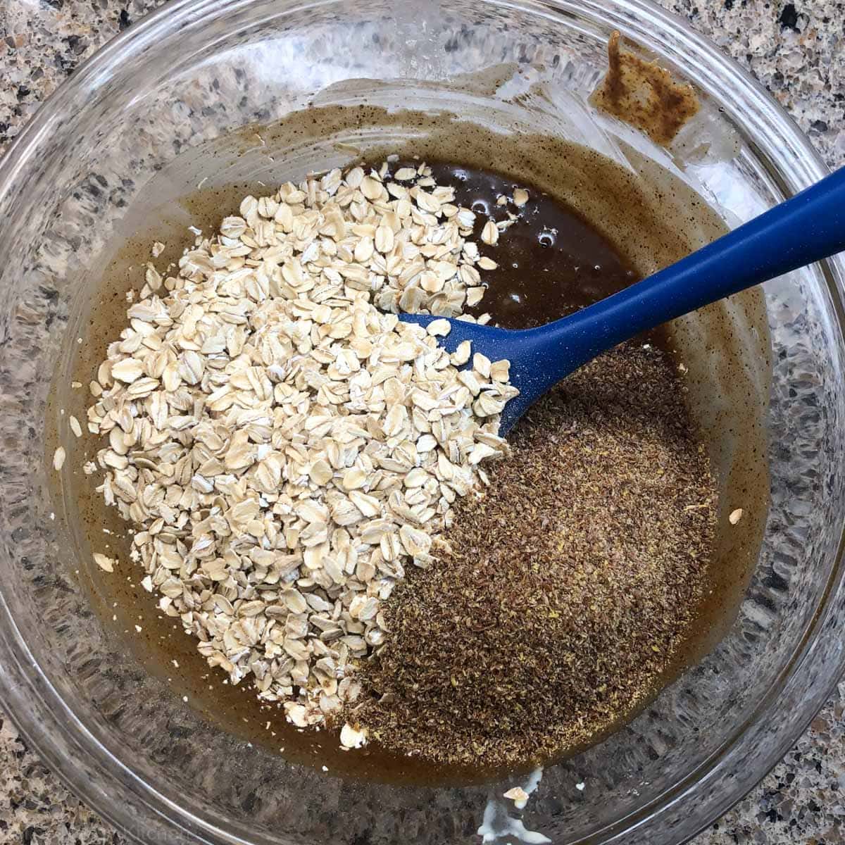 Oats and flax being mixed into a brown batter