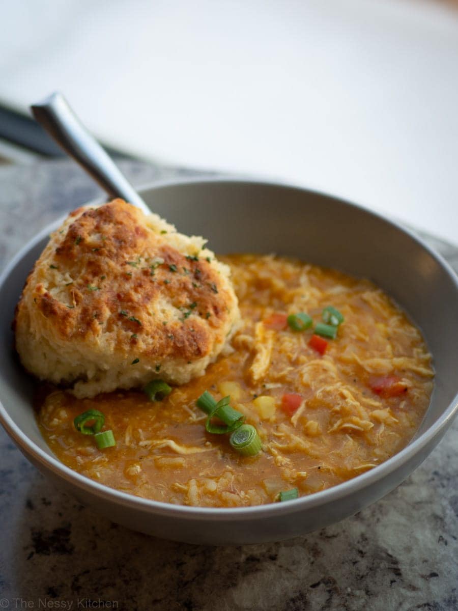 Bowl of soup topped with a biscuit.