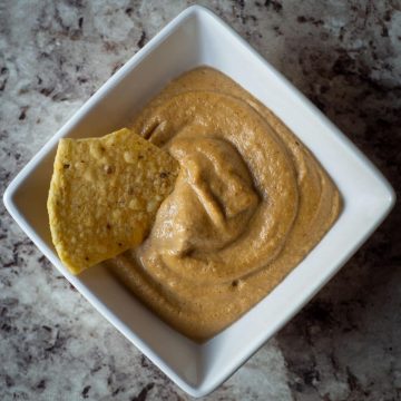 Tortilla chip dipped into a bowl of queso.