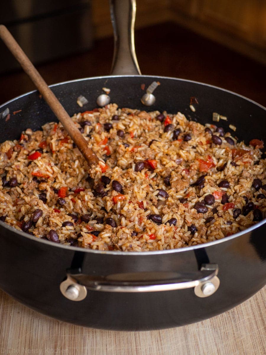 Rice and Chorizo with black beans in skillet with a wooden spoon.