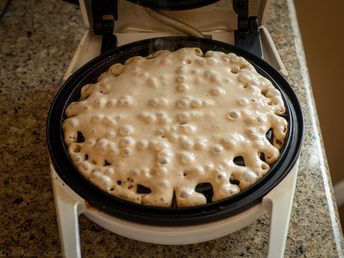 Oatmeal waffle batter on a waffle iron.