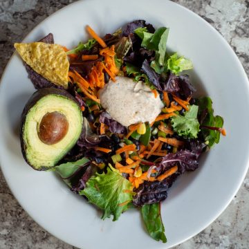 Bowl of Santa Fe salad topped with avocado and tortilla chips.