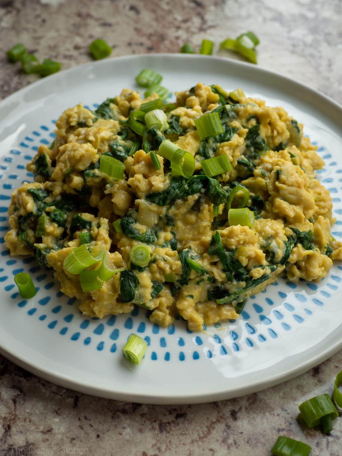Chinese inspired scrambled eggs on a plate topped with green onions.