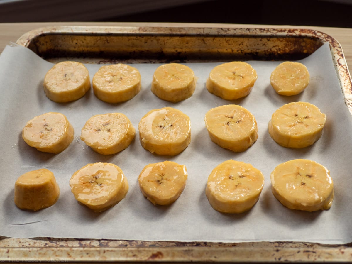 Plantain rounds spread out on a cookie sheet.