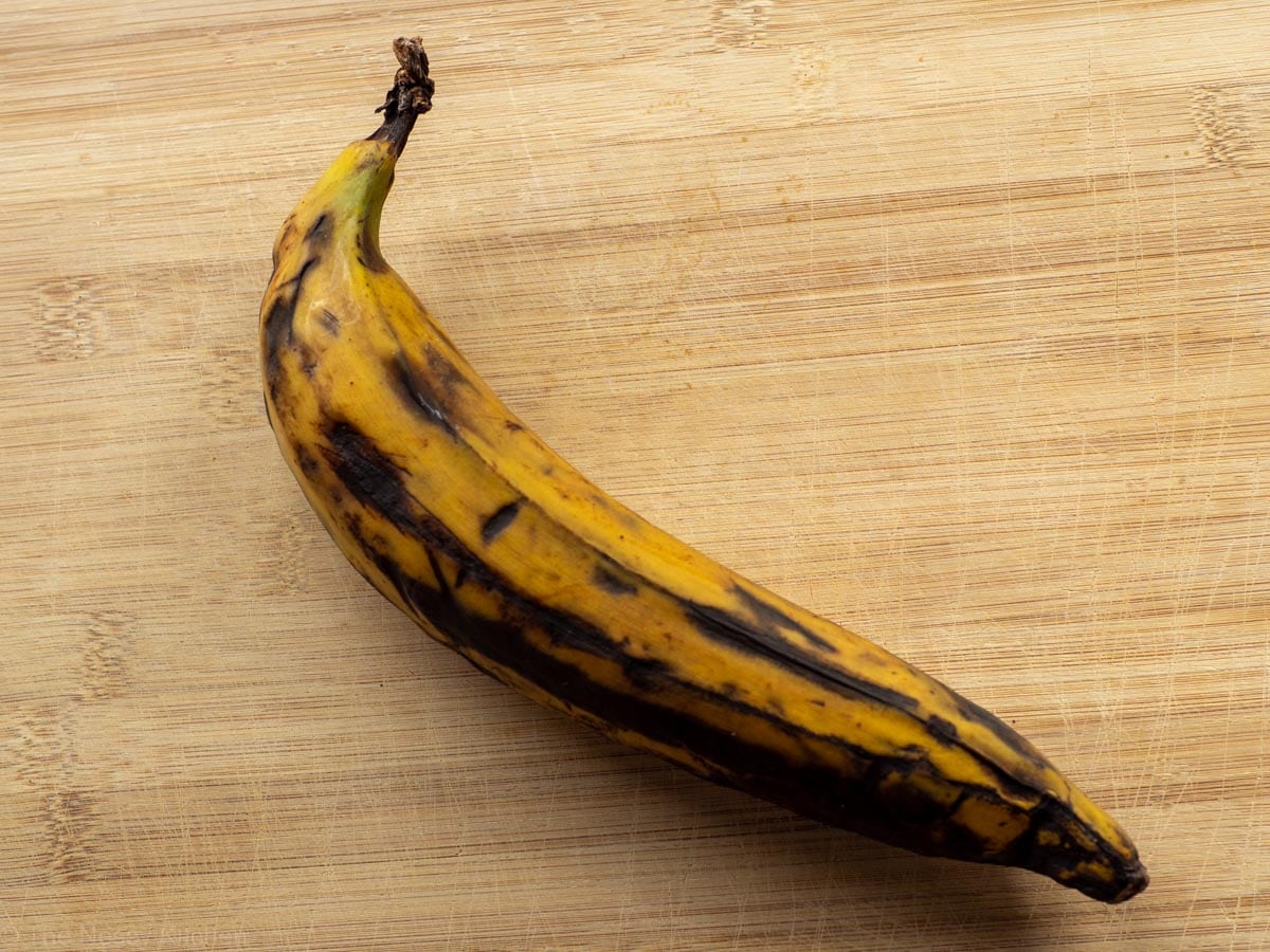 A ripe plantain that is yellow with black spots.