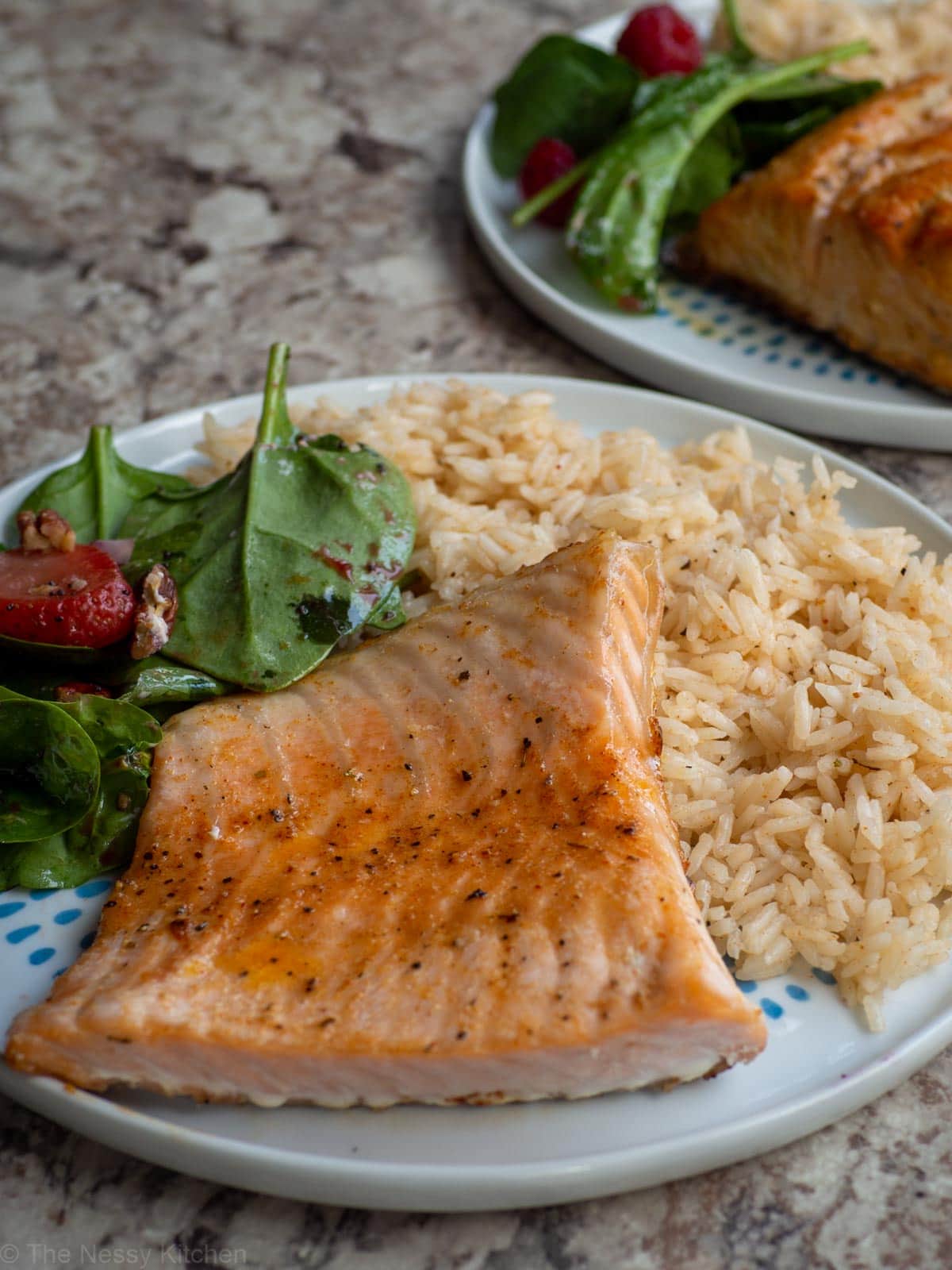 Cajun honey butter salmon on a plate with rice and salad.