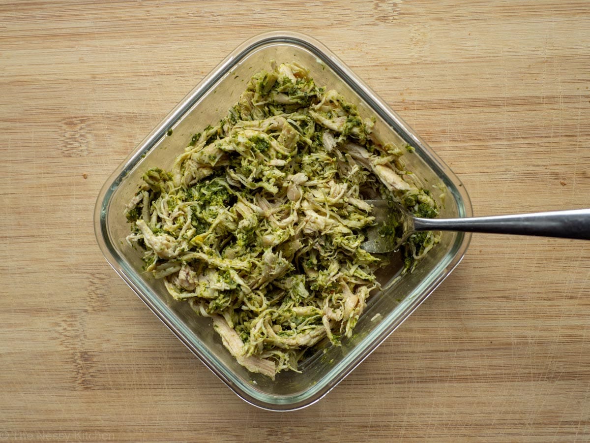 Chicken mixed with chimichurri in a glass dish.