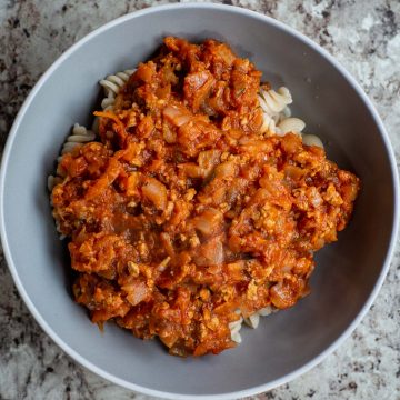 Pasta in a bowl topped with tomato turkey meat sauce.