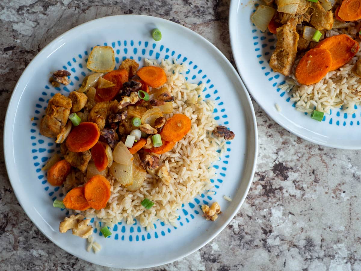 Cumin Chicken with Carrots and Onions on a plate with rice.