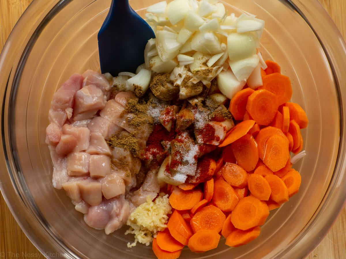 Mixing bowl with ingredients for chicken with carrots and onions.