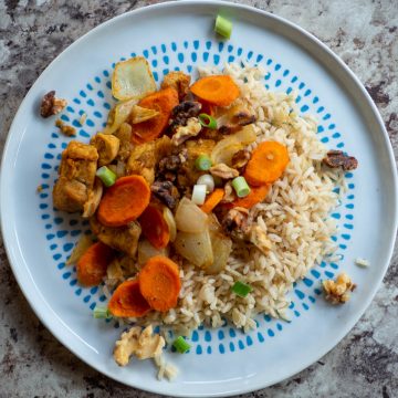 Plate of rice topped with chicken and carrots.