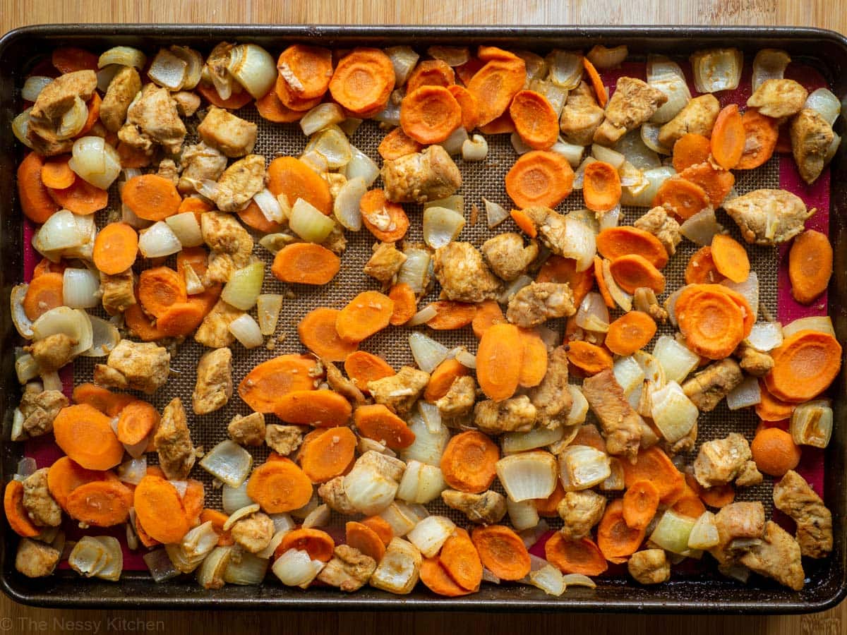 Chicken with carrots and onions on pan after baking.