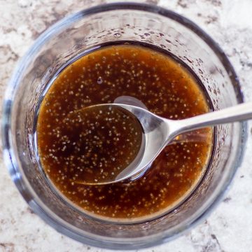 Glass bowl of vinaigrette with a spoon.