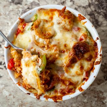 Ramekin filled with pizza ingredients and topped with cheese.