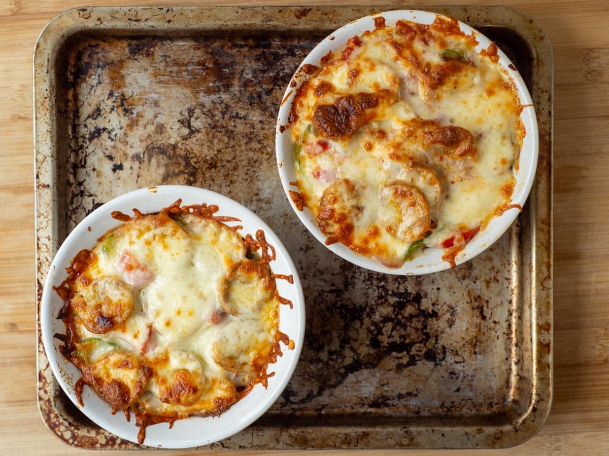 Baked pizza bowl ramekins on a cookie sheet.