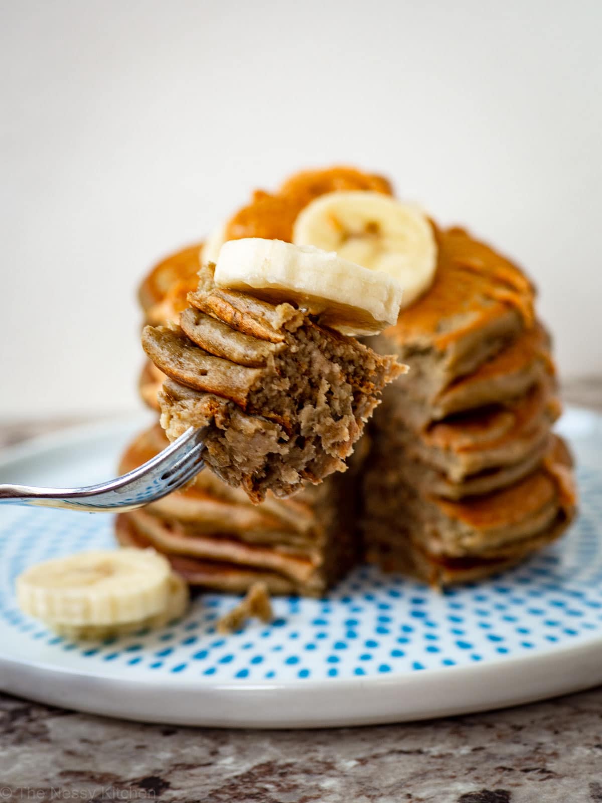 Bite of pancakes on a fork with a slice of banana.
