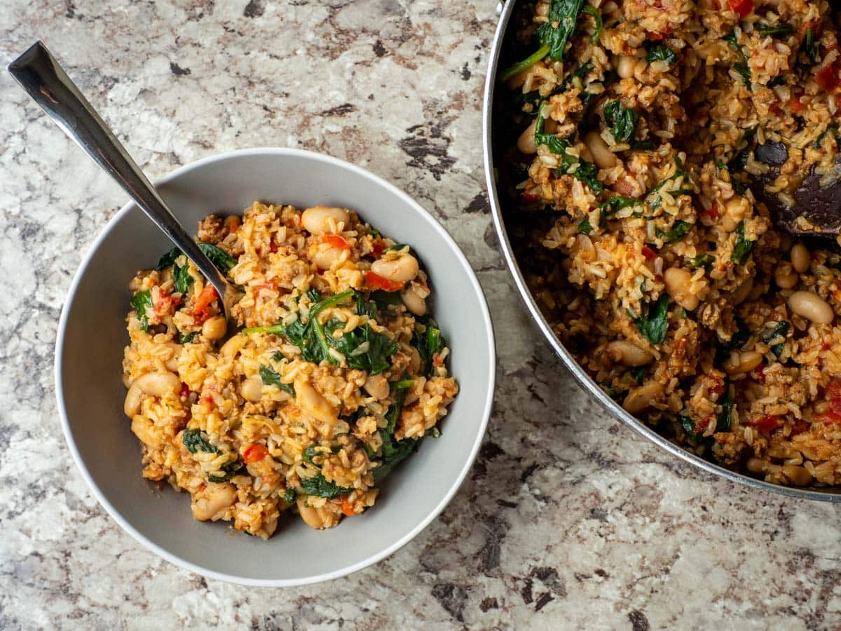 Italian sausage and rice skillet in a bowl next to the pot.