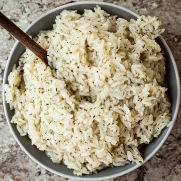 Bowl of lemon herb rice with a wooden serving spoon.