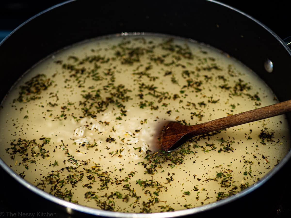 Water and herbs added to pot with rice.