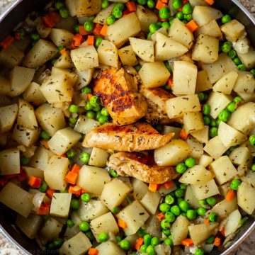 Skillet of potatoes, peas and chicken breast.