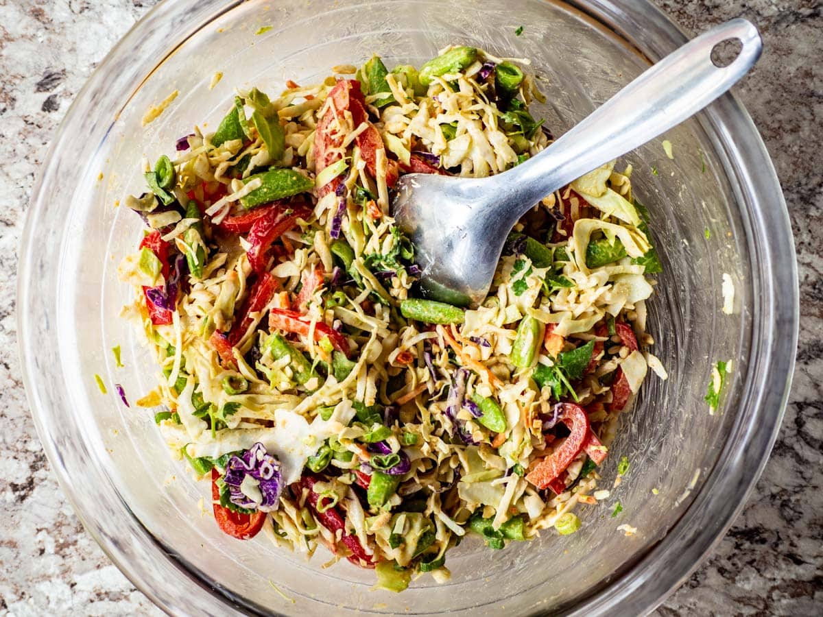 Peanut dressing mixed into chopped vegetables.