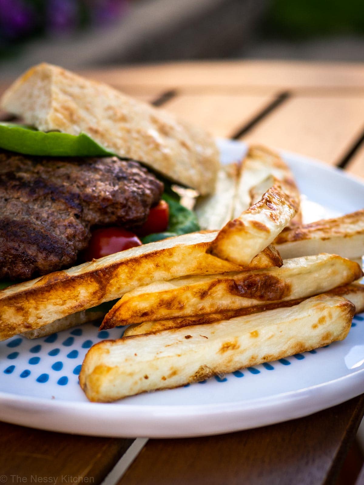 Oven baked fries on a plate with a burger.