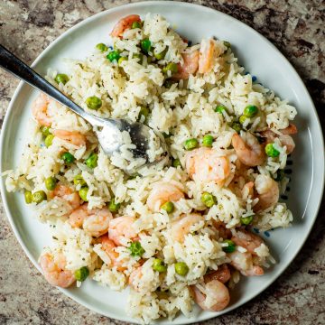 Plate of shrimp and rice with peas.