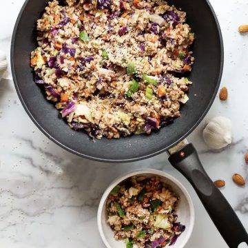 Fried rice in a skillet with a bowl spooned out alongside it.