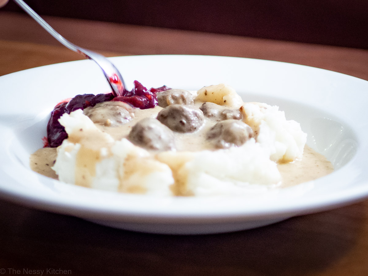 A spoon taking a spoonful of turkey Swedish meatballs and mashed potatoes. 