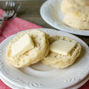 Sliced biscuit on a plate topped with butter.