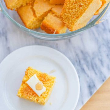 Cornbread on a plate topped with butter and honey.