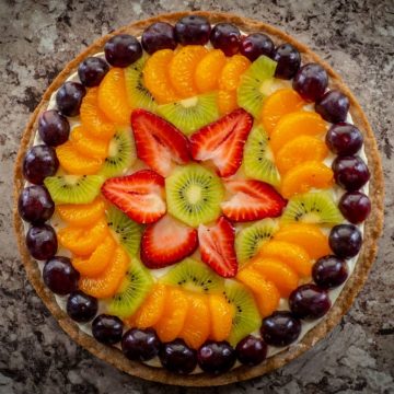 Fruit pizza topped with strawberries, kiwi and grapes.