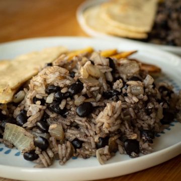 Plate of Costa Rican black beans and rice alongside tortillas and plantains.